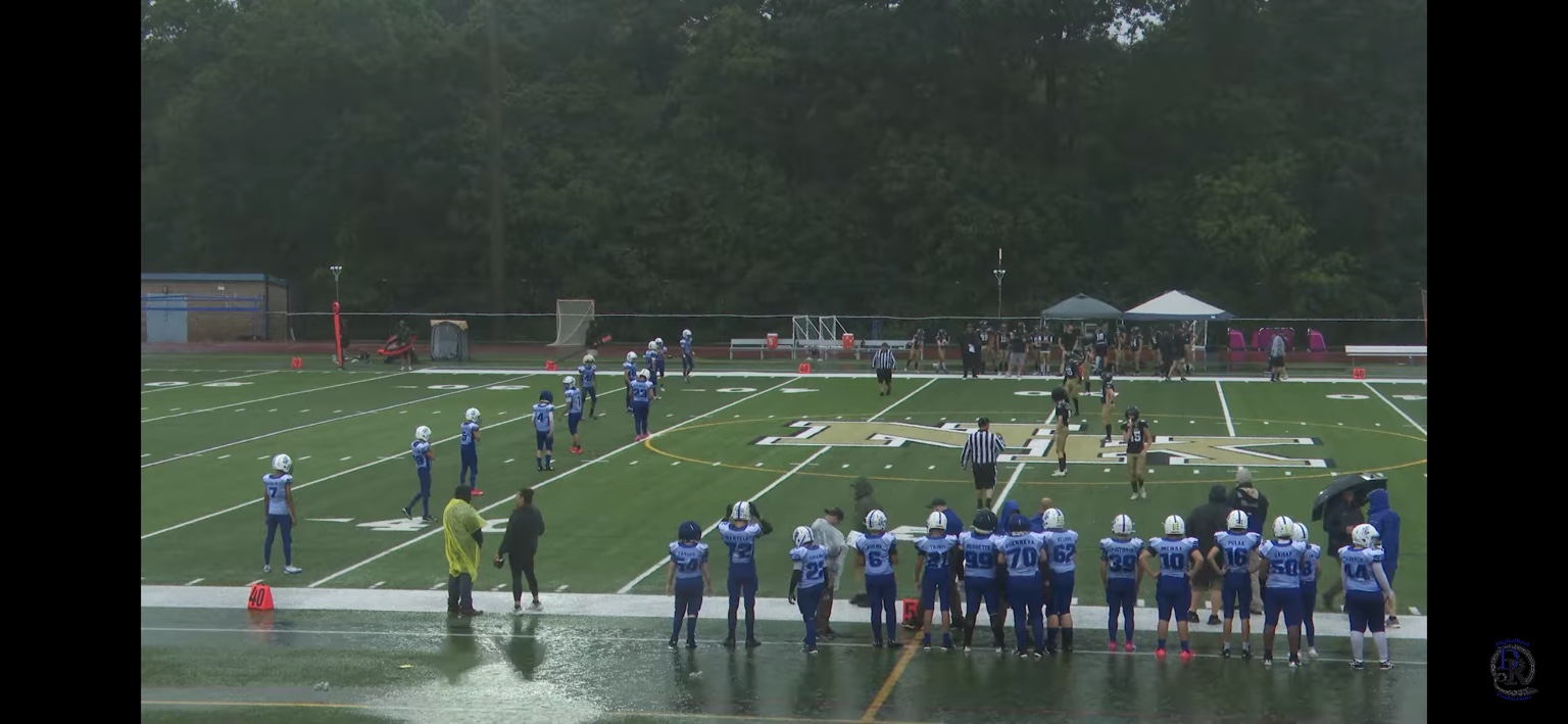 Cumberland players line up across a rain-soaked field against North Kingstown